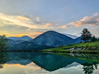 Scenic view of lake and mountains against sky during sunset