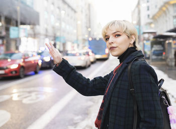 Portrait of young woman standing on street in city