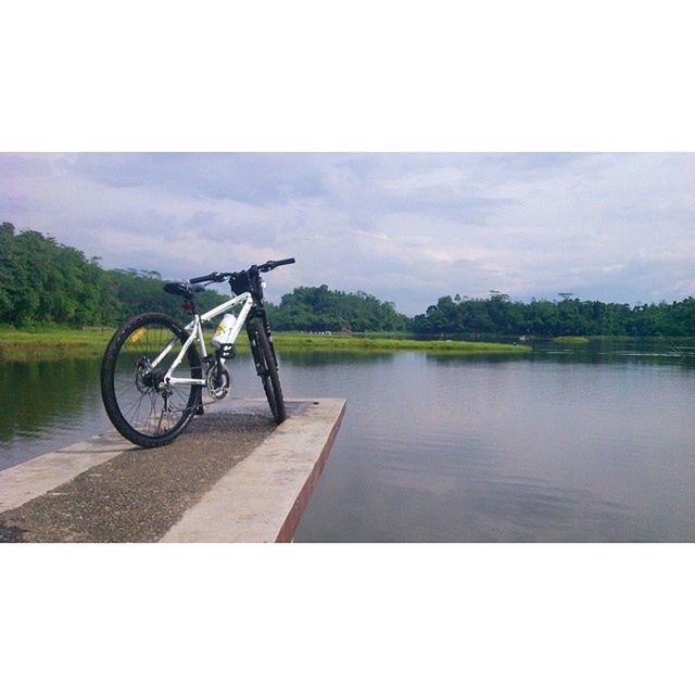 bicycle, transportation, water, mode of transport, sky, tranquility, lake, nature, tranquil scene, auto post production filter, tree, transfer print, cloud - sky, day, land vehicle, river, scenics, outdoors, beauty in nature, side view