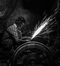 Side view of man working on metal