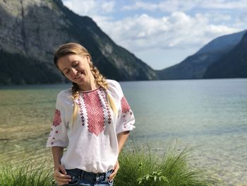 Woman standing by lake against mountains