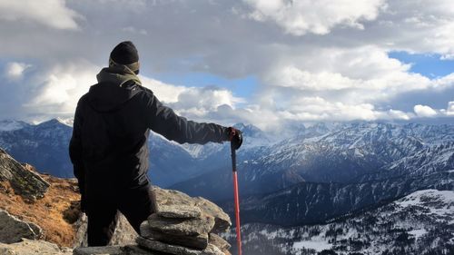 Man standing on snowcapped mountain against sky