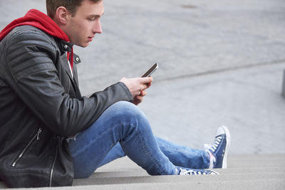 Side view of young man using mobile phone