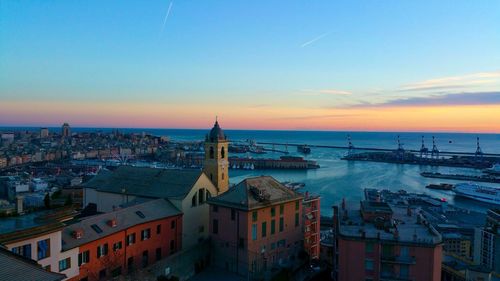 Residential district by sea against sky during sunset