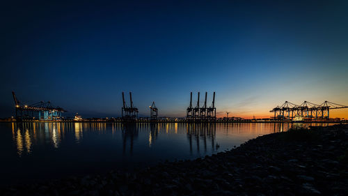 Pier at harbor against clear sky during sunset