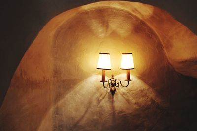Low angle view of illuminated lamp on wall
