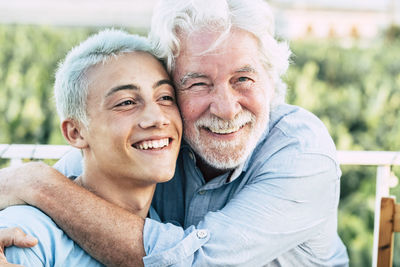 Portrait of grandfather embracing grandson outdoors