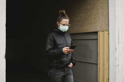 Woman wearing face mask using cell phone