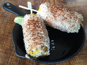 Close-up of corn cobs rolled in cheese and spices in cast iron pan