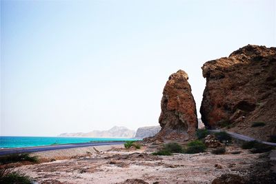 Scenic view of cliff by sea against clear sky