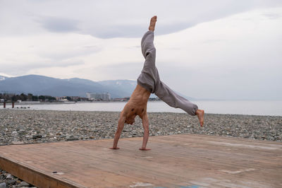 Full length of man doing handstand against sky