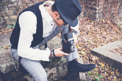 Mature man photographing while sitting outdoors during autumn