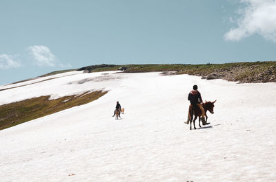 People riding horses on snow covered field