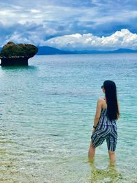 Rear view of woman standing in sea against sky