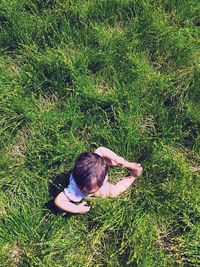 Directly above shot of baby sitting on field during sunny day