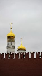 Red brick wall of kremlin and domes of orthodox cathedral behind