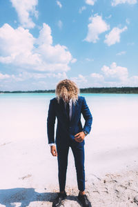 Rear view of woman standing on beach against sky