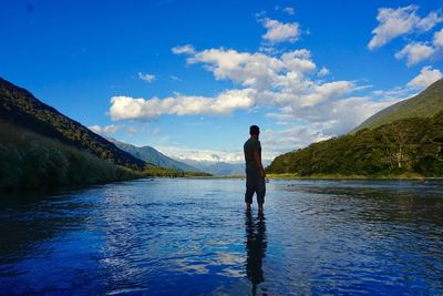 Man standing on lake against blue sky