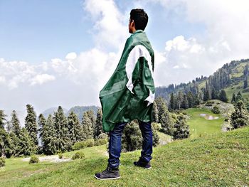 Rear view of man with pakistani flag standing on hill