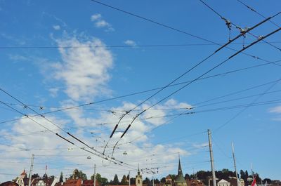 Low angle view of electricity pylon against cloudy sky