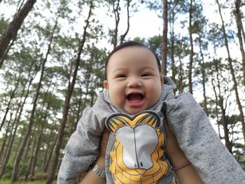 Portrait of cute smiling girl against trees