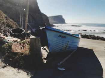 Deck chairs on rocks by sea against sky