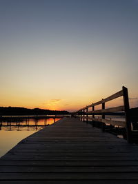 Pier over lake against sky during sunset