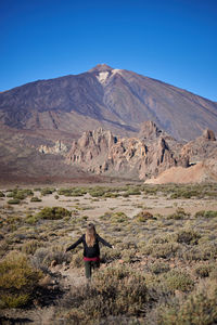 Rear view of man on arid landscape against clear sky