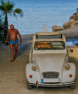 Rear view of shirtless man standing on beach