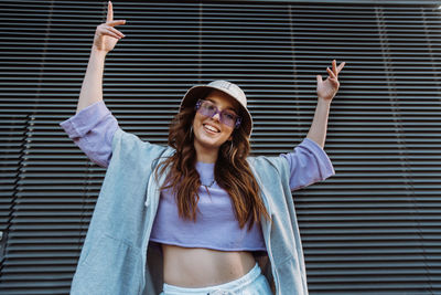 Portrait of young woman standing against wall