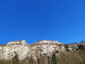 Low angle view of rocks against clear blue sky