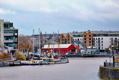 Boats moored at harbor by buildings in city