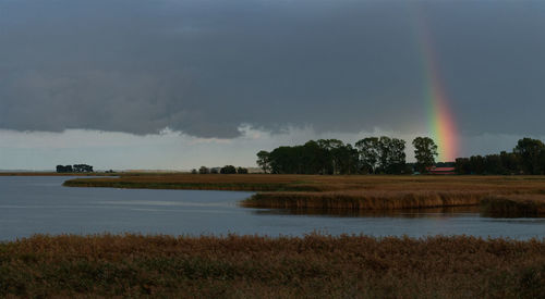 Scenic view of lake against rainbow in sky