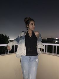 Portrait of young woman standing against sky at night