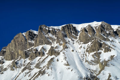 Low angle view of snow against clear blue sky