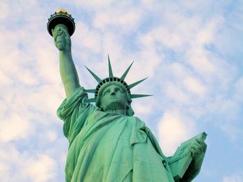 Low angle view of statue of liberty against cloudy sky