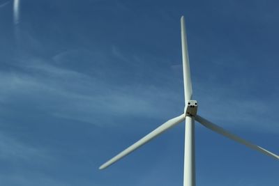 Low angle view of wind turbine against blue sky