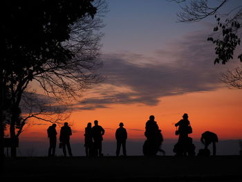 Silhouette people against orange sky