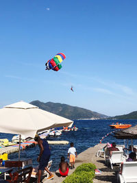 People paragliding over beach against sky