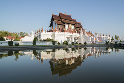 Reflection of building in lake against clear sky