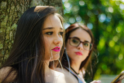 Close-up of female friends wearing pink lipstick against tree