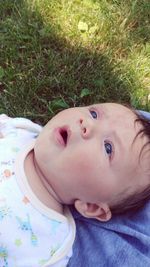 Close-up portrait of cute baby lying on grass
