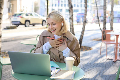 Young woman using laptop while sitting on chair