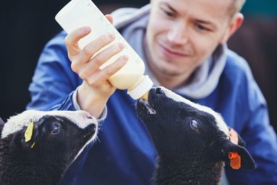 Smiling mid adult man feeding milk to lambs