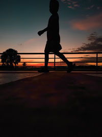 Side view of silhouette man standing against sky during sunset