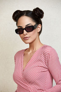 Young woman wearing sunglasses while standing against wall