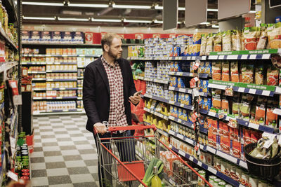 Man using smart phone while shopping in grocery store