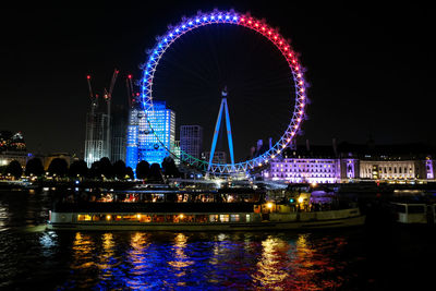 Illuminated ferris wheel in city at night