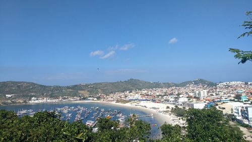 Aerial view of town by sea against blue sky