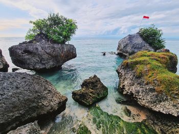 Beach view with white sand and coral rocks and indonesian flag